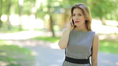 Parkta telefonda konuşan çekici genç bir kadın.