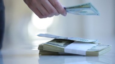 Kadın elleri dolar sayıyor ve masanın üstüne koyuyor.