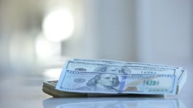Kadın elleri dolar sayıyor ve masanın üstüne koyuyor.
