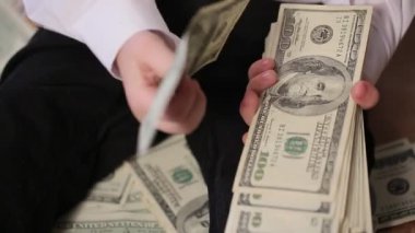 Genç çocuk dolarlarla oynuyor. Para kavramı.