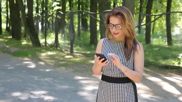 Felice Giovane Donna Con Gli Occhiali Utilizzando Smartphone Nel Parco — Video Stock