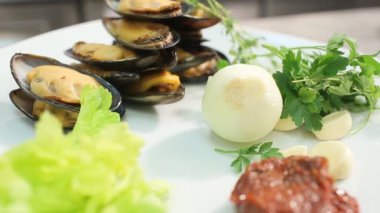 Beyaz tabakta midye, sarımsak, soğan ve salata yapraklı lezzetli gurme yemeği.