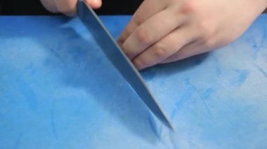 Erkek elleri mavi bir karatahtanın üzerinde taze sarımsak doğruyor.