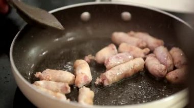 Mutfaktaki tavada leziz domuz sosisleri pişiriyorum.