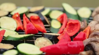 İnsanlar ızgarada biber, mantar ve kabak kızartıyorlar.