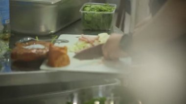 Tahtada pastırma ve soğan dilimleyen şef.