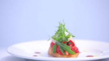 Somon balığı parçalı lezzetli sandviç ve beyaz tabakta roka.