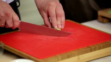 Yakın çekim şefi, tahtanın üzerinde Çin lahanası dilimliyor.