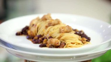 Lezzetli spagetti, kızarmış sosis ve beyaz tabakta fasulye.