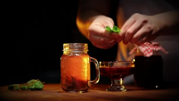 Świeża Czarna Herbata Szklanym Słoiku Liśćmi Mięty Drewnianym Stole — Wideo stockowe