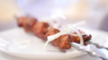 Beyaz tabakta taze kebap ve soğan yakın plan görüntüsü.