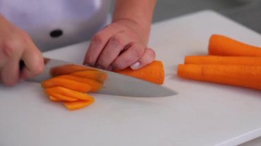 Şef kesme tahtasındaki bıçakla havucu kesti.