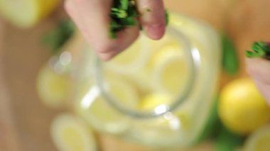 Birisi taze limonata ve kavun ve limonlu taze limonataya biraz nane yaprağı ekliyor.