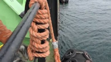 worker knits nautical knots to attach mooring fenders