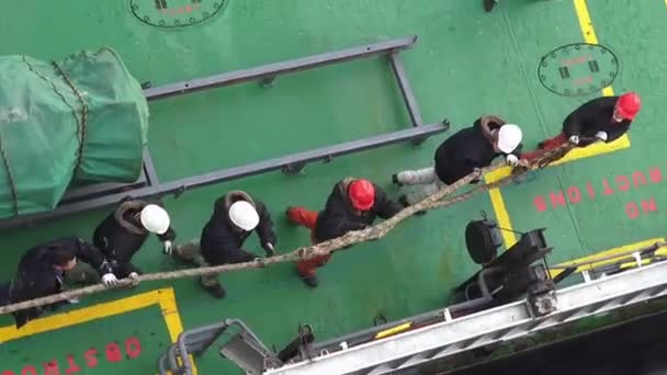 Sailors in helmets pull mooring end for fastening on bollard — 비디오