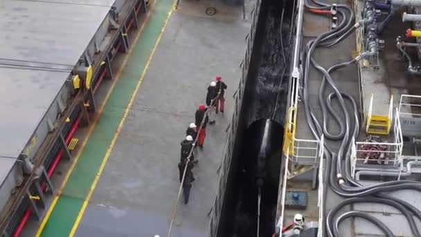 タンカーの船員はボラードに固定するために係留端を引く — ストック動画