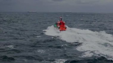 Hızlı pilot gemisi dalgalarla gri deniz suyu boyunca yol alır.