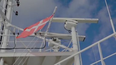 Danimarka bayrağı güçlü bir rüzgarla dalgalanıyor petrol tankerinde gökyüzüne karşı