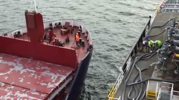 Tanker legt an Frachtschiff an und Matrosen nutzen Festmacherausrüstung — Stockvideo