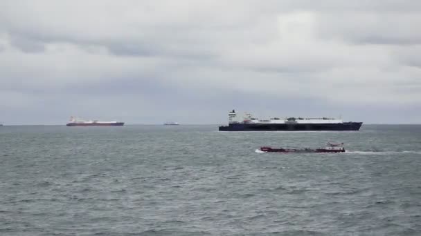 Pequeno petroleiro com velas de carga no mar contra grandes navios — Vídeo de Stock