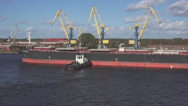 Sleepboot maakt snelle tanker aan te leggen met kranen op zonnige dag — Stockvideo