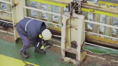 Güverte tayfası, tankerdeki pası enflasyon iğnesi tabancasıyla temizliyor.