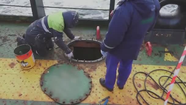 Механики меняют штифты люка грузового бака на нефтяном танкере — стоковое видео