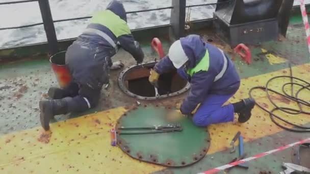 Scheepsarbeiders draaien pennen van vrachttank luik op olietanker — Stockvideo