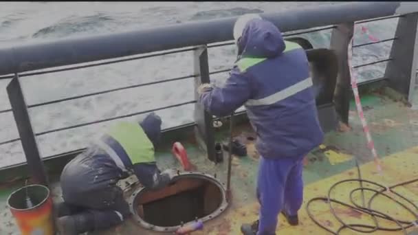 Рабочие меняют штифты грузового люка на нефтяной танкерной палубе — стоковое видео