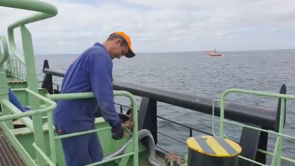 Bosun unhanks kedja på ledstång mot fartyg som rör sig långt bort — Stockvideo