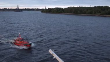 pilot motorboat sails on blue water surface past river bank