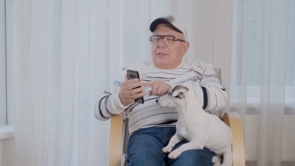 Glad senior man i tröja utforskar modern smartphone — Stockvideo