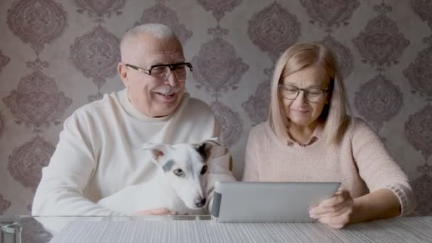 Bejaarde echtpaar met bril kijkt naar tablet scherm thuis — Stockvideo