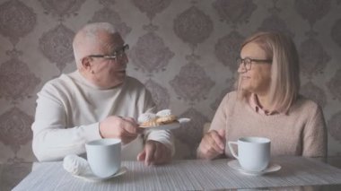 Neşeli yaşlı adam güzel karısına lezzetli kurabiyeler sunuyor.