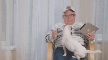 Çizgili kazak giyen yaşlı bir adam komik beyaz bir köpeği okşuyor.