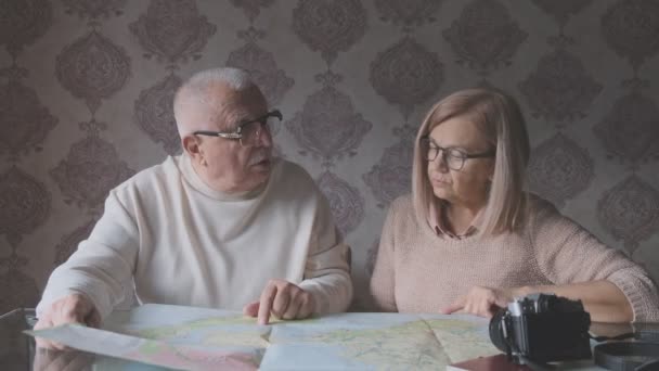 Senior husband in white cozy jumper explores map by wife — Stock Video