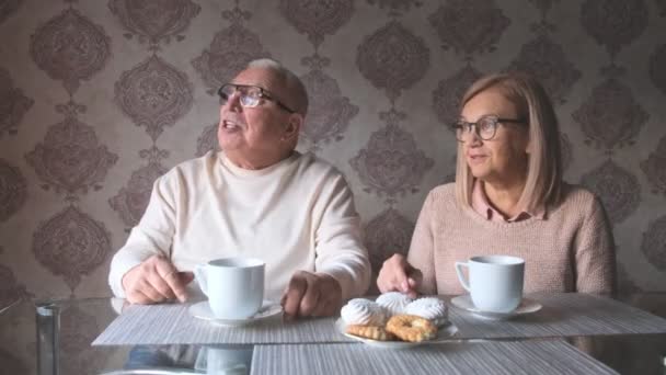 Madura casal fala sentado à mesa na frente de xícaras de chá — Vídeo de Stock