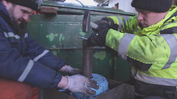 Mannen met hamer reparatie liermotor op industriële tanker — Stockvideo