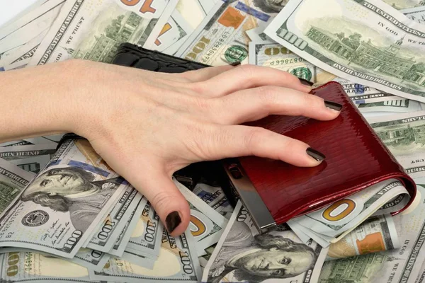 很多钱的百元钞票和两个钱包贪婪地张开手指躺着一只女性的手 — 图库照片