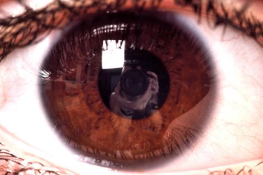 Kadın açık kahverengi gözleri ile öğrenci yansıması kamera ve fotoğrafçı