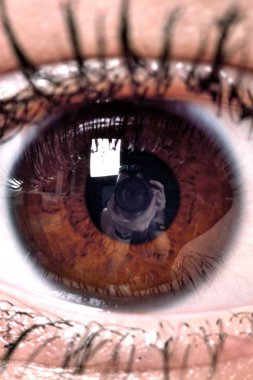Kadın açık kahverengi gözleri ile öğrenci yansıması kamera ve fotoğrafçı