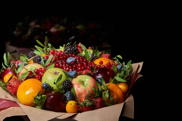 A delicious bouquet of healthy vitamin fruits and berries: strawberries, pomegranates, currants, persimmons, blueberries, tangerines on a black background.