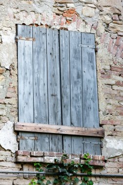 Paslı demir menteşeli, tuğla duvarlı ve antik taşlı İtalyan kırsal evinin pencere panjurları..