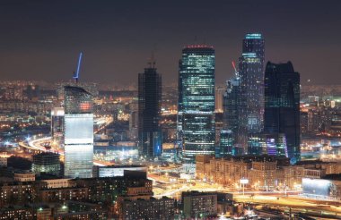 Çatılardan kışın gökdelenler gece city Moscow üzerinde göster..