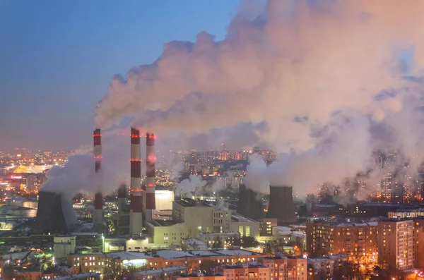 Vapor e fumaça das chaminés e torres de refrigeração da cidade Central de Aquecimento e Energia. A vista das alturas no crepúsculo, inverno — Fotografia de Stock