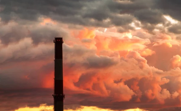 Chaminé industrial empilhar silhueta contra o fundo do céu tempestade ao pôr do sol — Fotografia de Stock