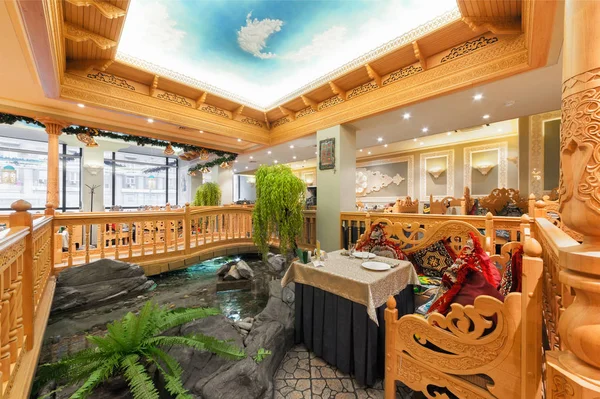 MOSCA / RUSSIA - DICEMBRE 2014 L'interno del ristorante di lusso della cucina uzbeka Babay Club in stile orientale. Un tavolo vicino al laghetto ornamentale e un ponte di legno — Foto Stock
