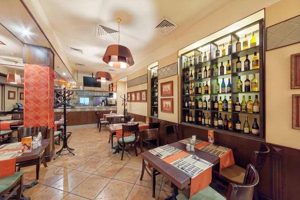 MOSCÚ - SEPTIEMBRE 2014: El interior de la barra de parrilla cafetería NA MEDOVOY. Amplio salón con mesas para visitantes. Estante de pared decorativo con botellas de vino —  Fotos de Stock