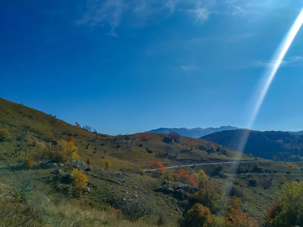 Зелене поле луки з барвистою природою в осінній блакитний день неба з сонячним світлом під час прогулянки в гірських пагорбах у спокійному відкритому середовищі — стокове фото