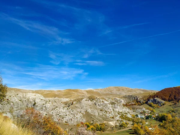 Cielo azul claro sobre la región montañosa desierta y las colinas de piedra grises. Otoño caída soleado día claro con hojas amarillas en los árboles y el paisaje rústico en Bosnia — Foto de Stock